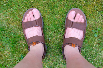 Two feet with sandals on grass background