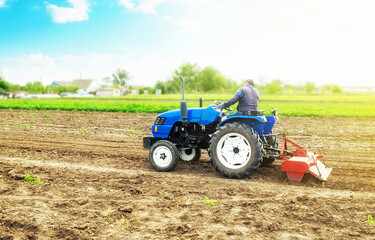 Farmer on a tractor with milling machine loosens, grinds and mixes soil. Field preparation for new...