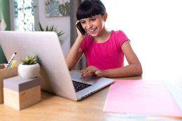 smiling daughter imitating her mom telecommuting with cellphone and computer
