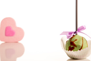 Cake pops and pink heart on white background place for text
