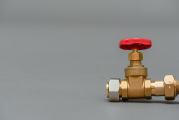 Red valve on a water pipe close up on a gray background with copy space.