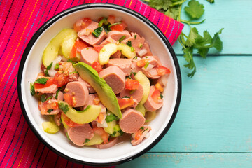 Mexican sausage ceviche with avocado on turquoise background