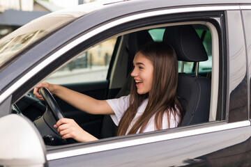 Obraz na płótnie Canvas Happy young woman driving her new car