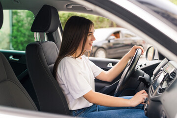 Naklejka premium Driving around city. Young attractive woman smiling and looking straight while driving a car