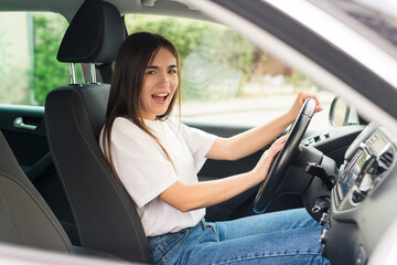 Young woman hand pressing the horn button while driving a car through the road.