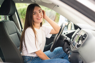 Cheerful young woman learning to drive on her own car