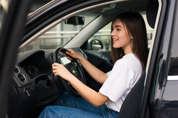 Naklejka premium Pretty young woman driving her new car in saloon