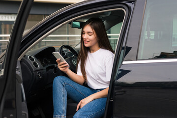 Fototapeta na wymiar Young woman use phone while sitting in her new car
