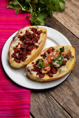 Mexican molletes with chorizo and fresh sauce on wooden background