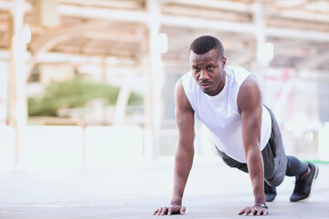 Fototapeta na wymiar african american man is outdoor exercising by push up Look strong, clearly see the muscles in the upper arm