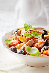 Penne pasta baked with pork tenderloin, cherry tomatoes, black olives and cheese. Close up.