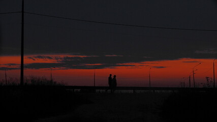 silhouette of two people on the night road