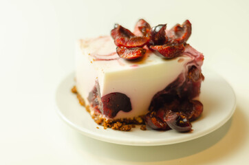 Japanese cheesecake with cherry sauce and fresh cherries on the ceramic plate and red background