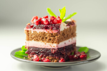 Colorful multi-layered cream chocolate cake with cherry jam and pomegranate