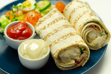 Tortilla wrap with chicken and beechwood smoked bacon served with mix salad on the blue plate