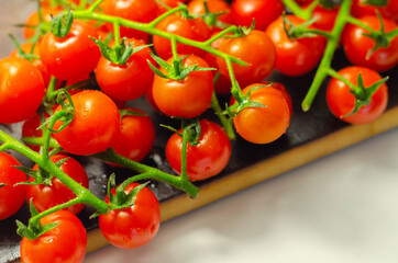 Covered with drops of water, fresh tomatoes with sprigs on wood