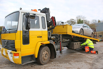 man loading car on a recovery truck	