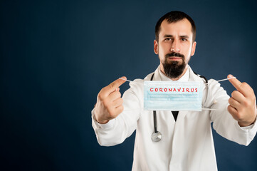 Male doctor with stethoscope in medical uniform showing protective mask