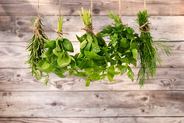 Collection of cooking herbs hanging for drying against grey wooden background