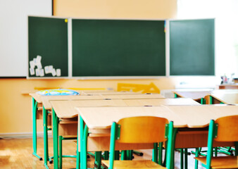 an empty schoolroom, desks, chairs, a green blackboard. The concept of back to school, no people, education.