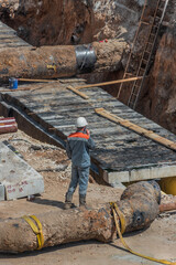 Construction worker at the underground trench: laying and installation of urban centralized water supply and sewage. 