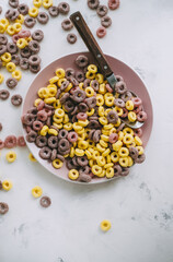 Multi-colored corn rings on a pink plate for breakfast, healthy food.
