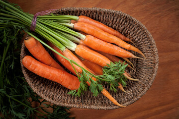 organic ripe carrots in a basket on a wooden table