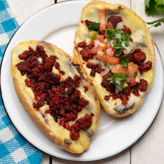 Mexican molletes with chorizo and fresh sauce on white background