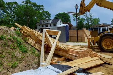 A wooden roof truss being lifted by a boom truck forklift in the roof a new home