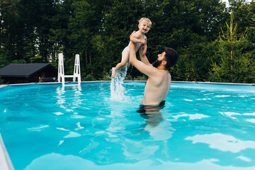 Father and son having fun together in outdoor swimming pool