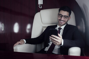 Young handsome businessman travelling first class, sitting in armchair next to window, reading text...