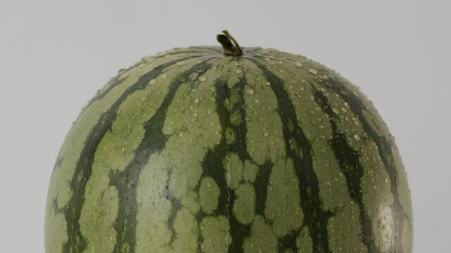 Ripe watermelon with drops of water on a white background, close-up. Wet watermelon on a white background. Drops of water dripping on a watermelon. Ripe berry watermelon. Organic healthy food concept