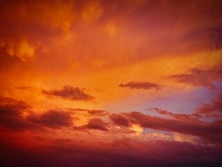 Rain clouds are colored orange by the light of the setting sun over the horizon