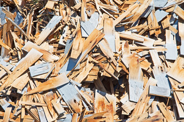 A pile of discarded cedar wall shingles which have been removed from a house under renovation