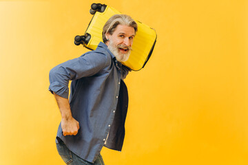 Stylish laughing bearded man holding a yellow suitcase.