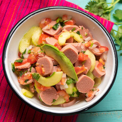 Mexican sausage ceviche with avocado on turquoise background