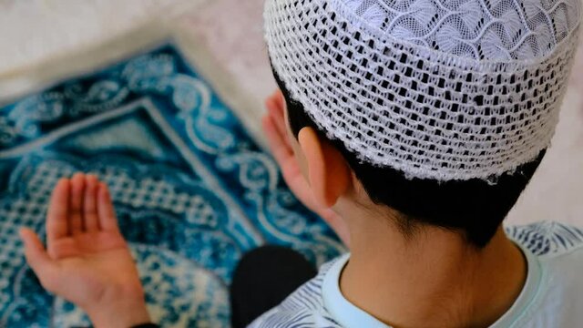 a young muslim boy praying, small young muslim is praying,