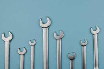 Set chrome spanner keys lying side by side on blue background. Flat lay, top view, minimal composition