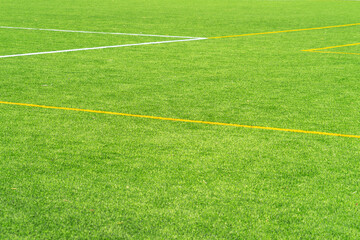 Obraz premium Green artificial grass turf soccer football field background with white and yellow line boundary. Top view