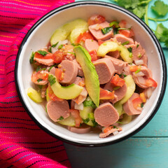 Mexican sausage ceviche with avocado on turquoise background