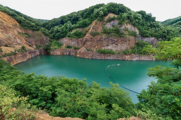 Beautiful Lake Ledinci (serbian: Ledinacko jezero) near Fruska Gora in Serbia, once there was a stone pit. Beautiful vibrant green deep mountain lake, hidden and surrounded by rocks and woods.