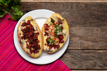 Mexican molletes with chorizo and fresh sauce on wooden background