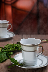 cups of steaming black tea accompanied by mint branches on rustic wooden table
