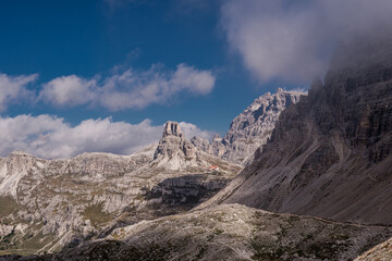 Dolomites Alps. Italy. Desert view from Tre Cime di Lavaredo. Alpine valley with canyon & dolomite peaks on background of blue sky and white clouds