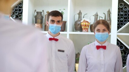 Employees of a restaurant in protective masks after quarantine. Interaction with restaurant manager and his staff on the terrace