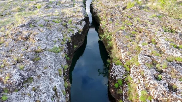 Narrow mountain river flowing through rocky landscape. Stream bed cut deep into stones. Upstream of Cijevna (Cem) in Montenegro. Aerial footage.