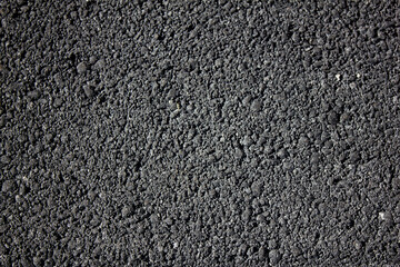 Gray porous texture of freshly laid asphalt from a distance. Background for text or pattern for design