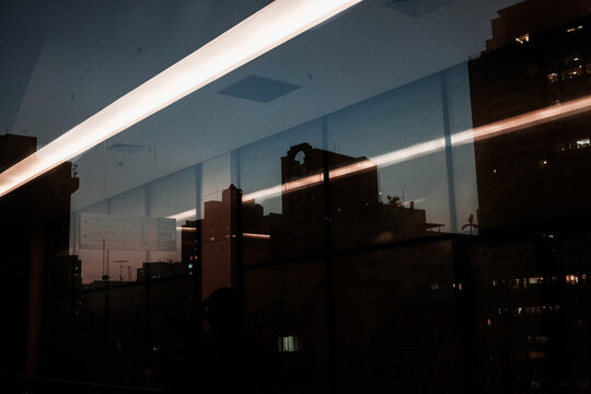 Silhueta de prédios em um final de tarde com reflexos de iluminação no vidro.