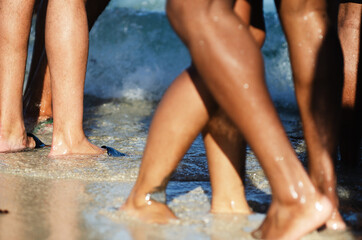 Close-up of the legs of unrecognizable young people enjoying the beach in golden sunlight