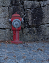 Vintage, red metal fire hydrant against an old stone wall in rural Portugal. Close up.